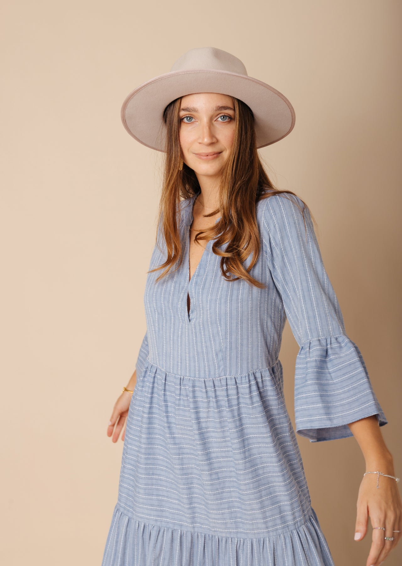 Mujer con vestido celeste largo y sombrero blanco.